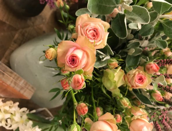 Close up of peachy pink roses in green vases