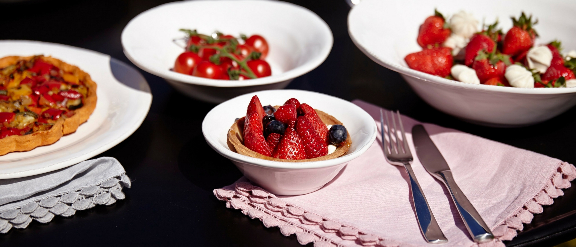 Fresh fruit in white ceramic bowls with pink napkins