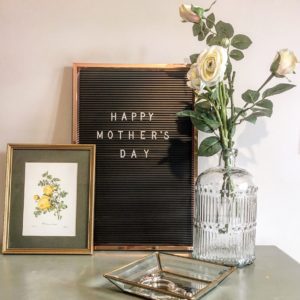 Glass bottle vase on dressing table with white faux roses