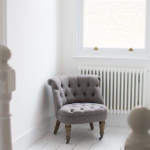 Soft grey button back chair against radiator