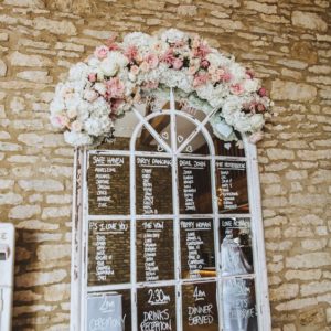 Wedding seating plan on window mirror with flowers