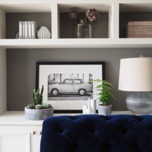 Open shelving with decorative items and blue sofar