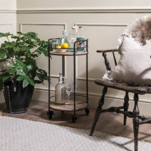 Drinks trolley next to plant and chair with cushion 